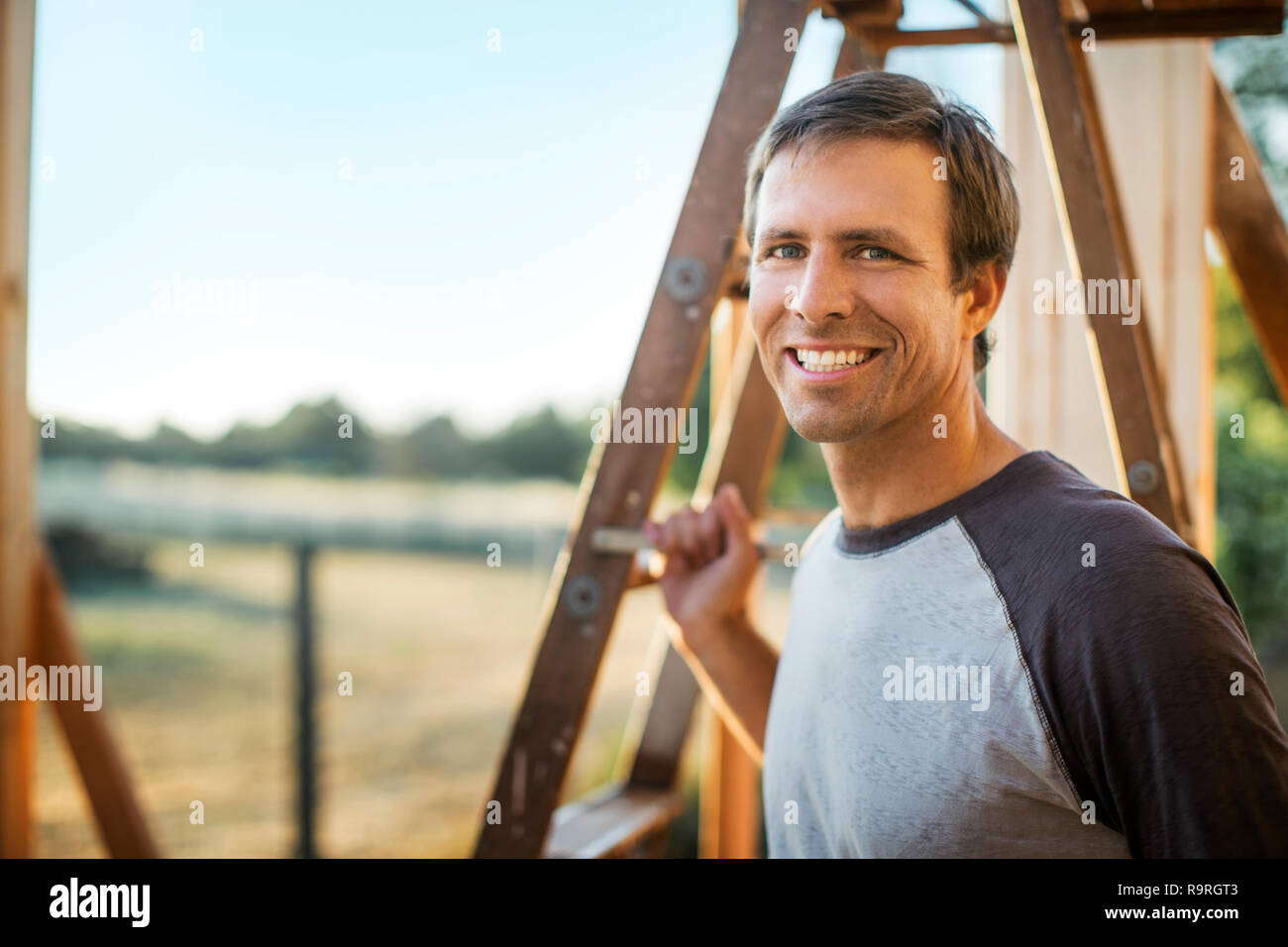 Lächelnd Mann steht neben einer Leiter in einem Haus im Bau. Stockfoto