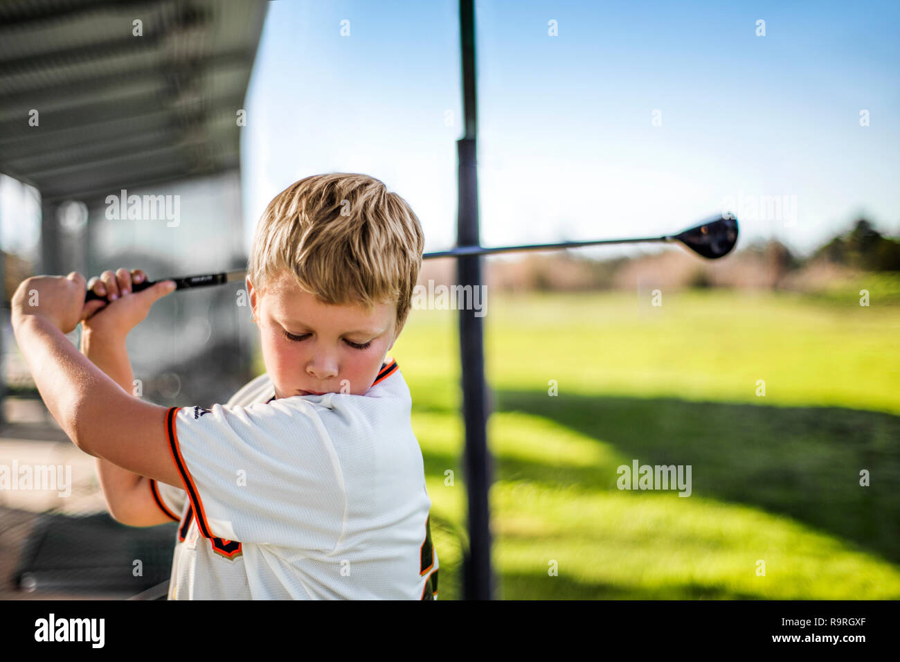 Junge Schwingen einer Golf Club auf einer Driving Range. Stockfoto