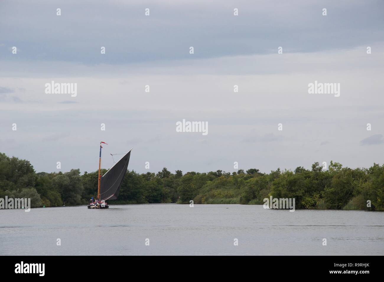 Traditionelle Norfolk wherry, einem Englischen/Britischen Segelboot mit einem großen schwarzen Segel, auf ranworth Breite in der Norfolk Broads, an einem grauen Tag Stockfoto