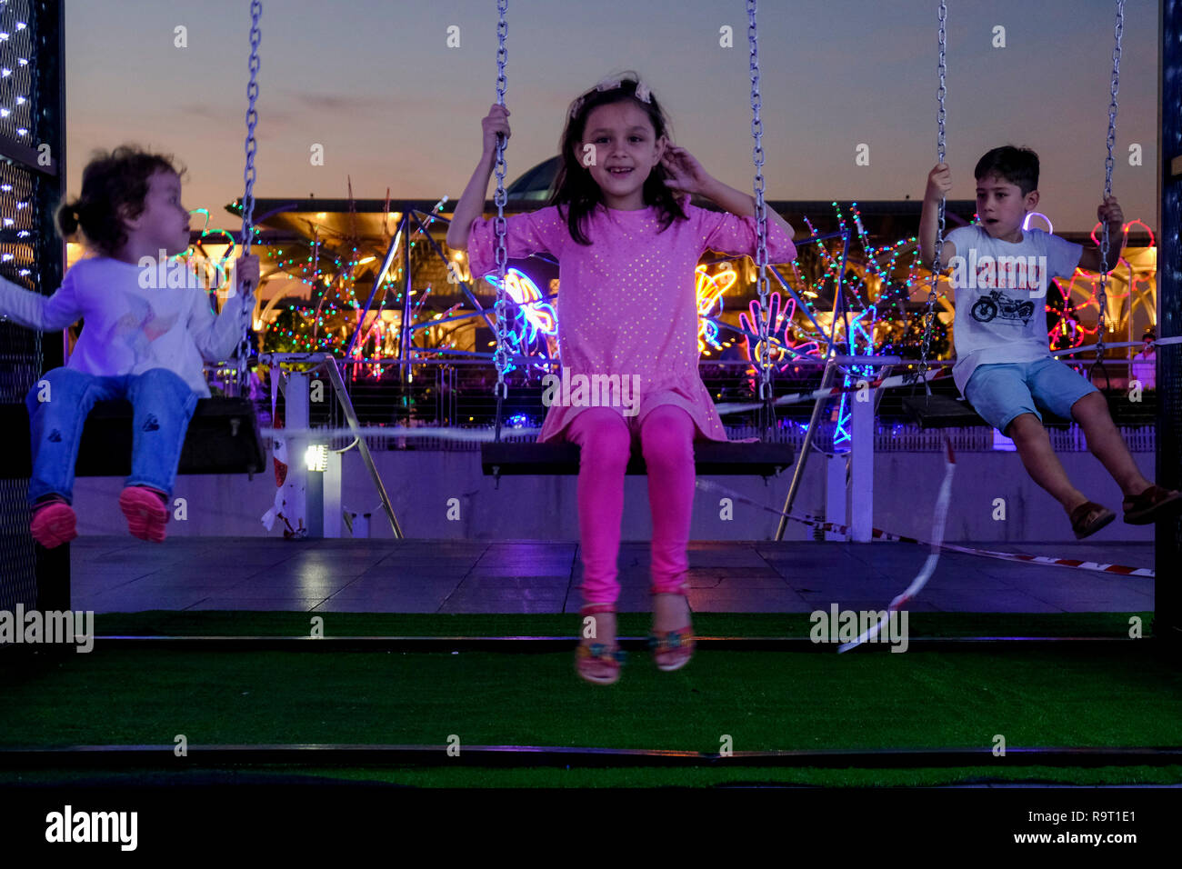 Süße kleine ausländische Kinder, die im Moment auf einer Schaukel an Licht und Bewegung Putrajaya (LAMPU) Festival 2018. Licht und Bewegung Putrajaya auch bekannt als LAMPU Festival am 28. bis 31. Dezember jeden Jahres statt. Das diesjährige Thema ist "Farben der Putrajaya'. Stockfoto
