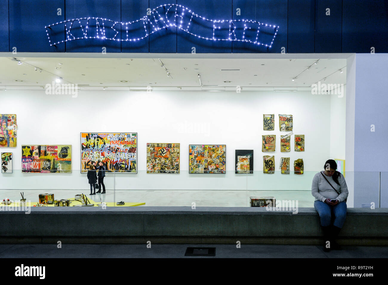 Krakau, Polen. 28 Dez, 2018. Eine Frau gesehen Sitzbereich neben dem Eingang von Boris Lurie Pop-art nach dem Holocaust Ausstellung, wo ein Zeichen ähnlich der über Auschwitz gate sagt ''Art macht Sie frei''. Boris Lurie (1924-2008) ist ein US-amerikanischer Künstler jüdischer Herkunft, geboren in Leningrad (heute St. Petersburg). Im August 1941 begannen die Deutschen, die Abschiebung der lokalen jüdischen Bevölkerung in das Ghetto in RIga, wo Boris Lurie seine Kindheit verbrachte. Seine Großmutter, Mutter, Schwester und Geliebte wurden in einem Wald in der Nähe von Rumbuli in der Rigaer Vorstadt im Dezember 1941 erschossen. Seine Arbeit ist eng re Stockfoto