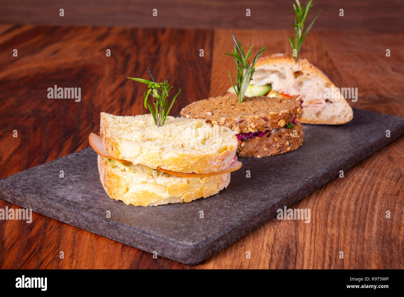Drei Sandwiches mit Salat, Schinken, Käse und Tomaten auf Marmor tisch. Stockfoto