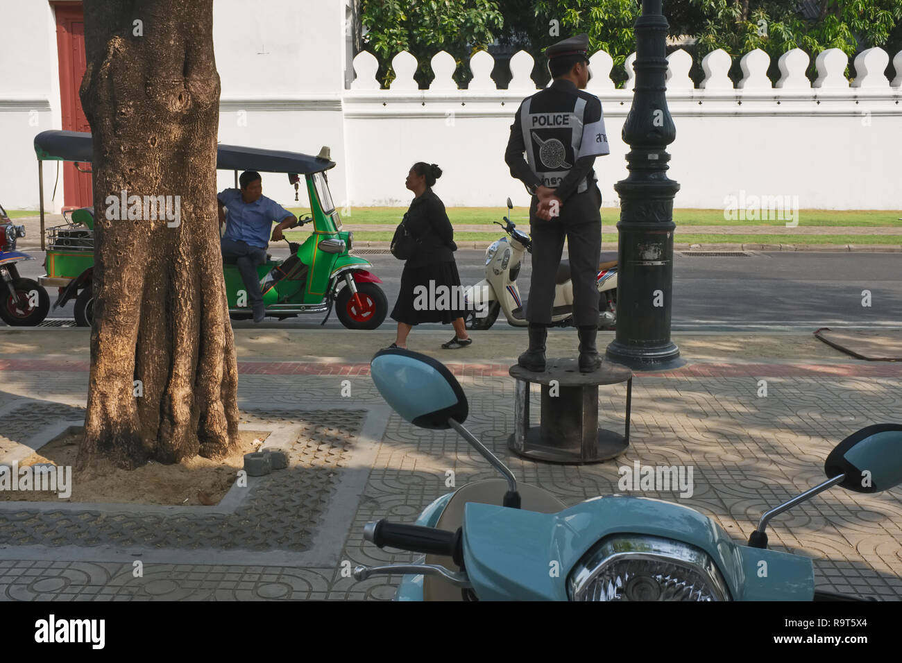 Ein Polizist vor Wat Po, Bangkok, Thailand, steht auf eine leere Kabelrolle für eine bessere Ansicht Stockfoto