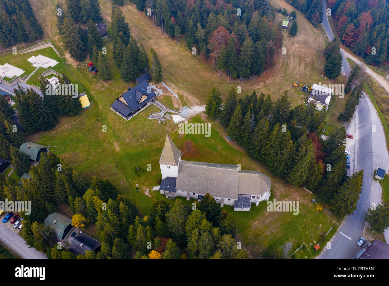 Luftaufnahme von Mountain Resort im Sommer, Trije kralji auf Pohorje, Slowenien mit Kabinen, Skipisten und eine Kirche Stockfoto