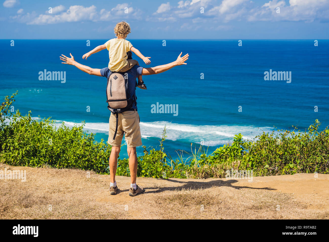 Vater und Sohn Reisende auf einer Klippe über dem Strand. Leere Paradies Strand, blaues Meer Wellen in Insel Bali, Indonesien. Von Suluban und Nyang Nyang statt. Mit Kindern unterwegs Konzept Stockfoto