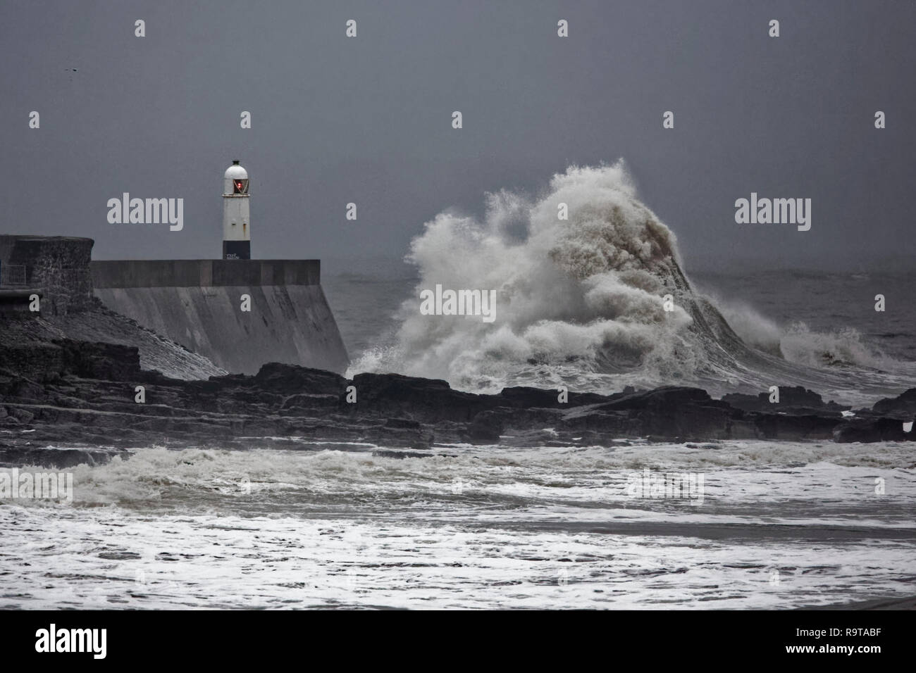 Im Bild: Wellen gegen die Promenade an der Wand durch den Leuchtturm in Porthcawl, South Wales, UK. Dienstag, 18 Dezember 2018 Re: Starker Regen ist für. Stockfoto