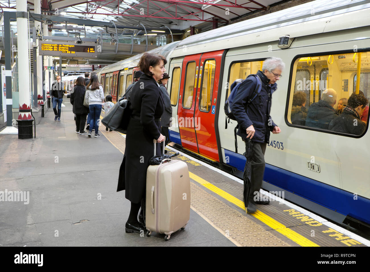 Die Menschen warten auf die Plattform mit dem Gepäck an Bord eines Hammersmith und City-Bahn in einer U-Bahn Station in London, England, UK KATHY DEWITT Stockfoto