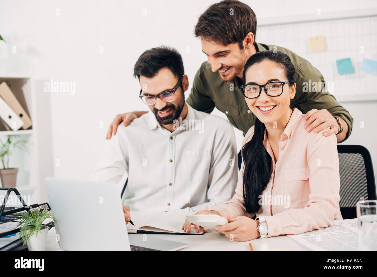 Lächelnd Office Manager am Schreibtisch und Mitarbeiter ständigen Sitzen im Büro Stockfoto