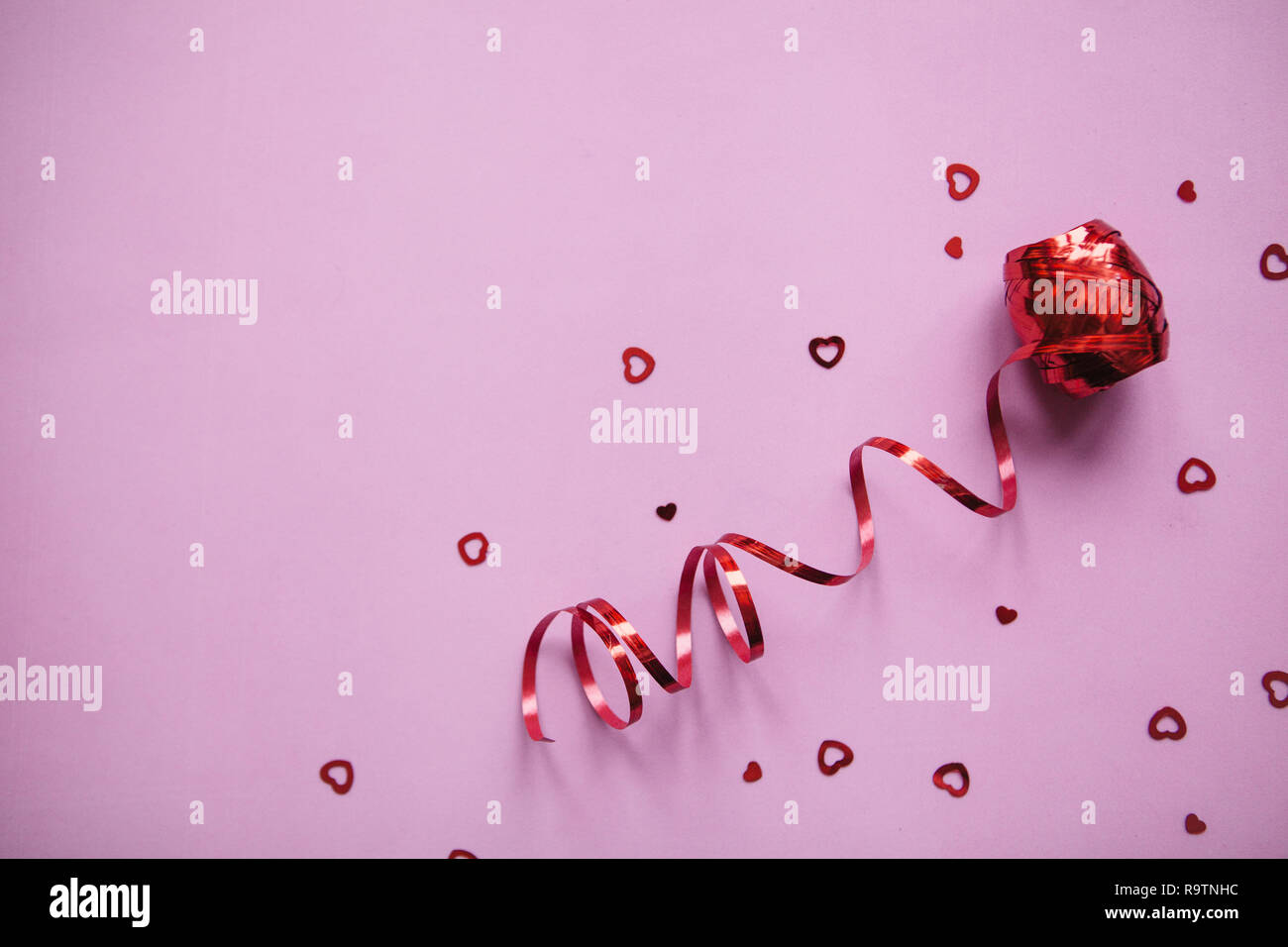 Red Ribbon und viele kleine Herzen. Valentine's Day Feier Konzept im minimalistischen Stil. Urlaub Elemente. Stockfoto