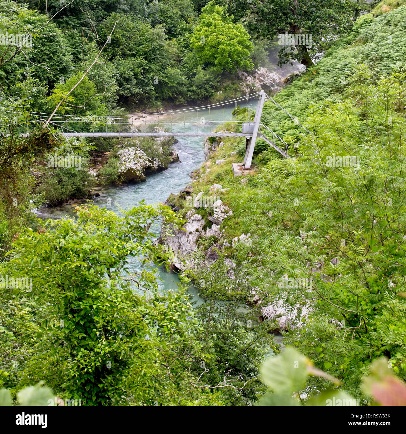 Eine Fußgängerbrücke über den Fluss kümmert, Asturien, Spanien. Stockfoto