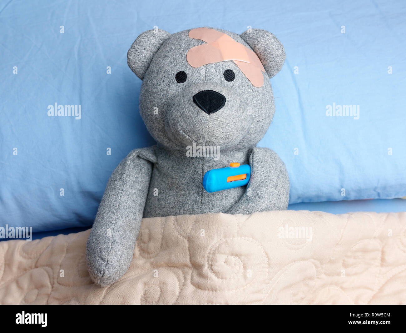 Verletzte Teddy Bear putze Kopf Bett thermometer Grippe Stockfoto