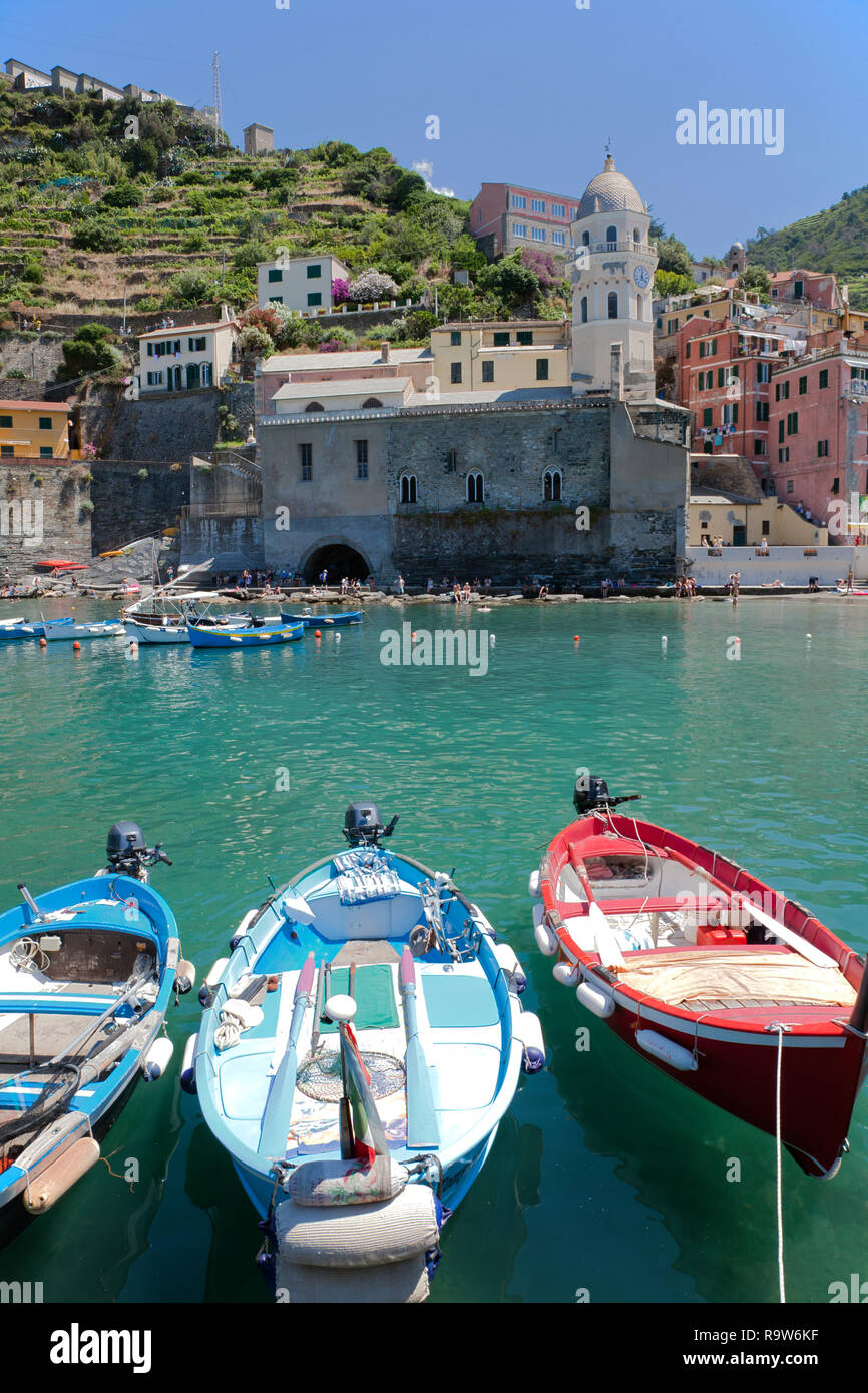 Fischerboote bringen Farbe in Vernazza Hafen, einer der fünf Städte, die in Italien berühmten Cinque Terre. Santa Margherita d'Antiochia im Hintergrund. Stockfoto