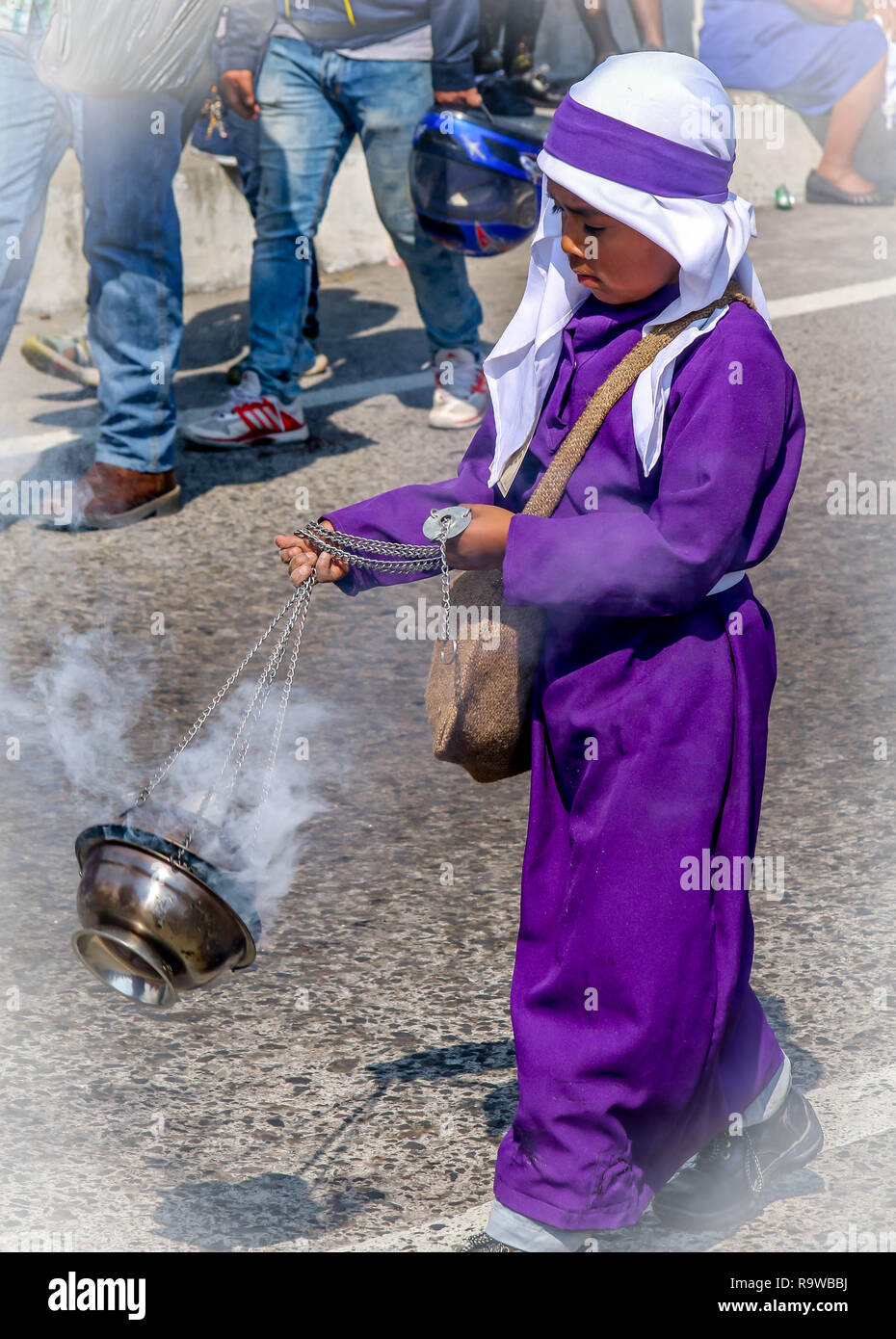 Ein lila gekleidete junge schwingen Weihrauch vor Ostern katholische Prozession in Guatemala Stockfoto