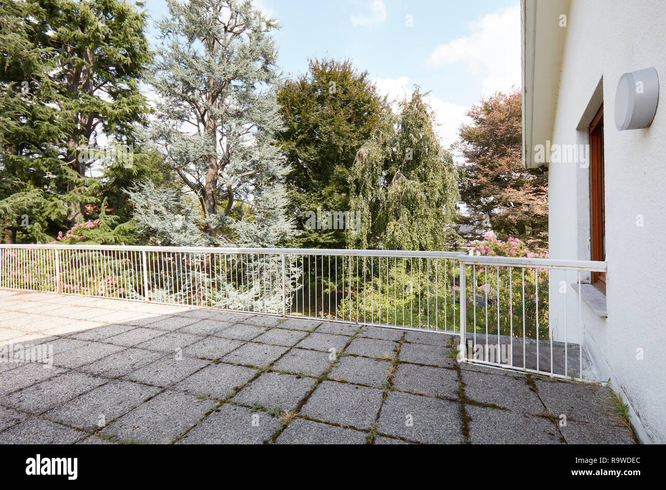 Große Terrasse im Landhaus mit Steinfliesenboden, große Bäume in einem sonnigen Tag anzeigen Stockfoto