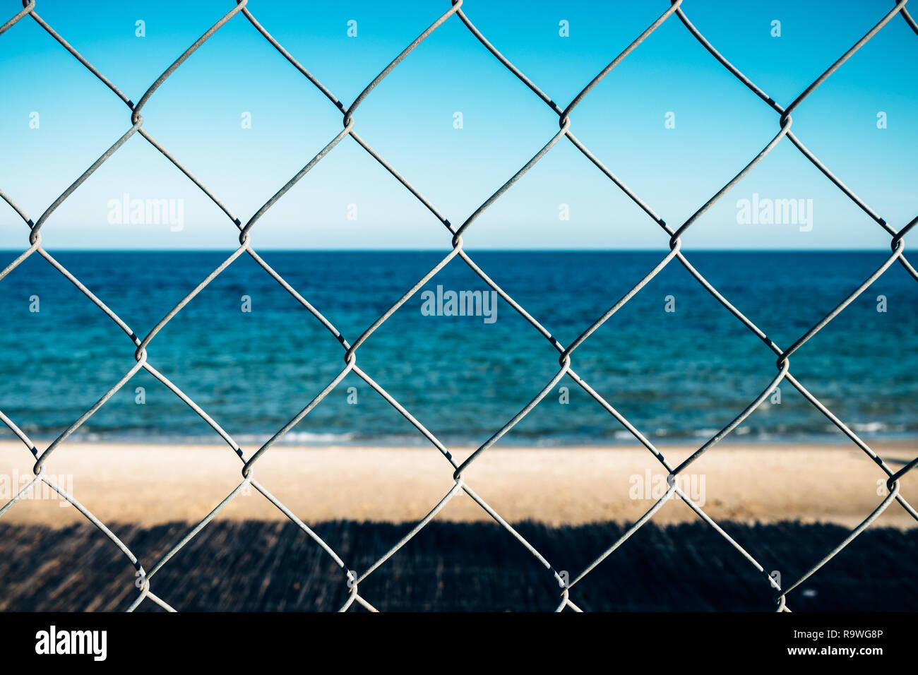 Anzeigen von leeren Sandstrand durch chain-link Fence am sonnigen Sommertag. Stockfoto