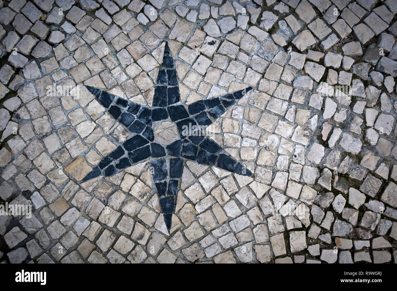 Spielen mit verschiedenen Formen und Muster einer gepflasterten Straße von Lissabon (Portugal). Schwarz 6-Stern von weißen Kopfsteinpflaster umgeben. Stockfoto