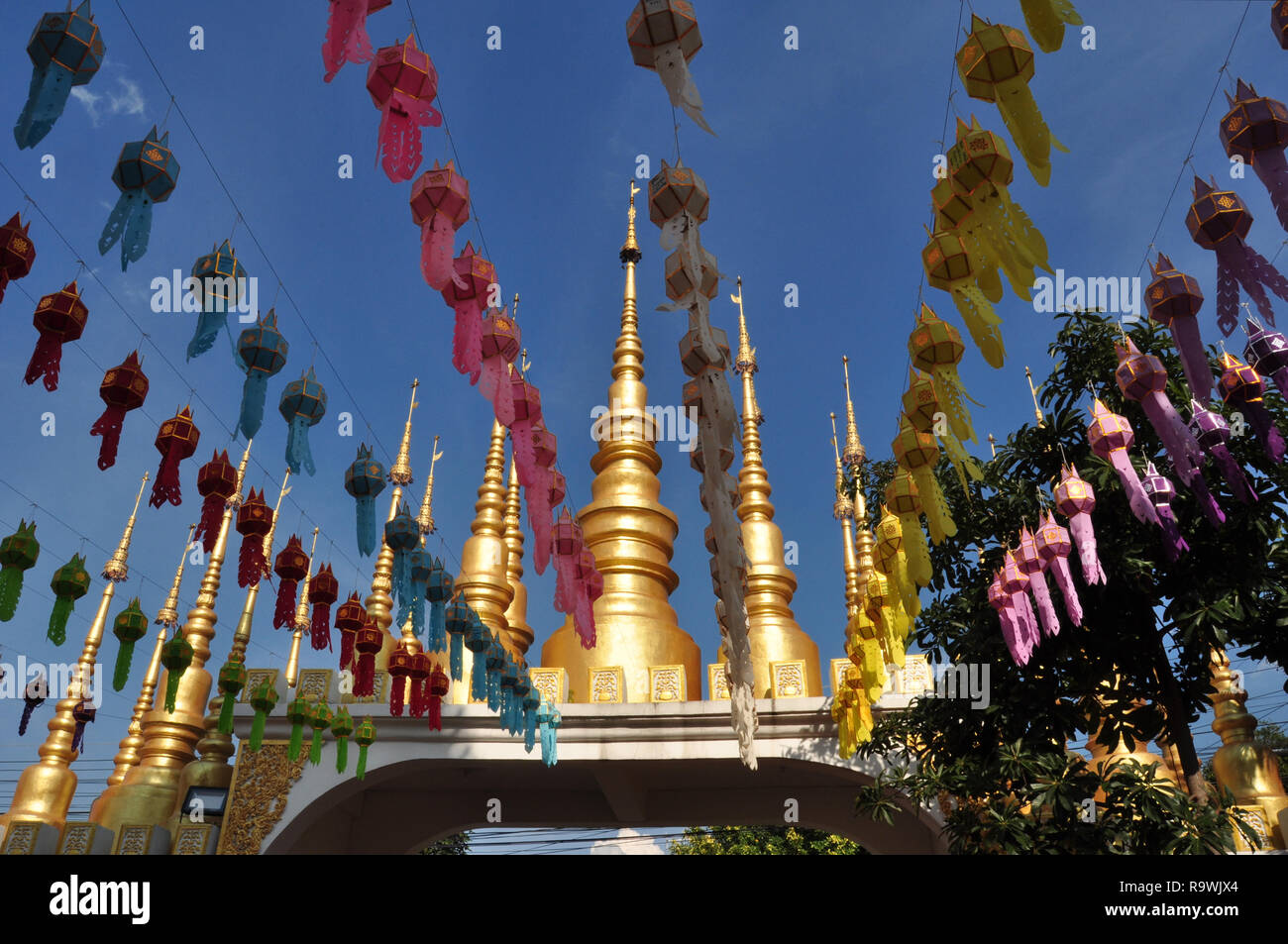 Willkommen, Wat Phong Sunun, Phrae, Nord Thailand, Eingangstor des Wat, vergoldete Pagoden mit Spitze, Bettwäsche in den Reihen mit Laternen, verschiedene Farben Stockfoto