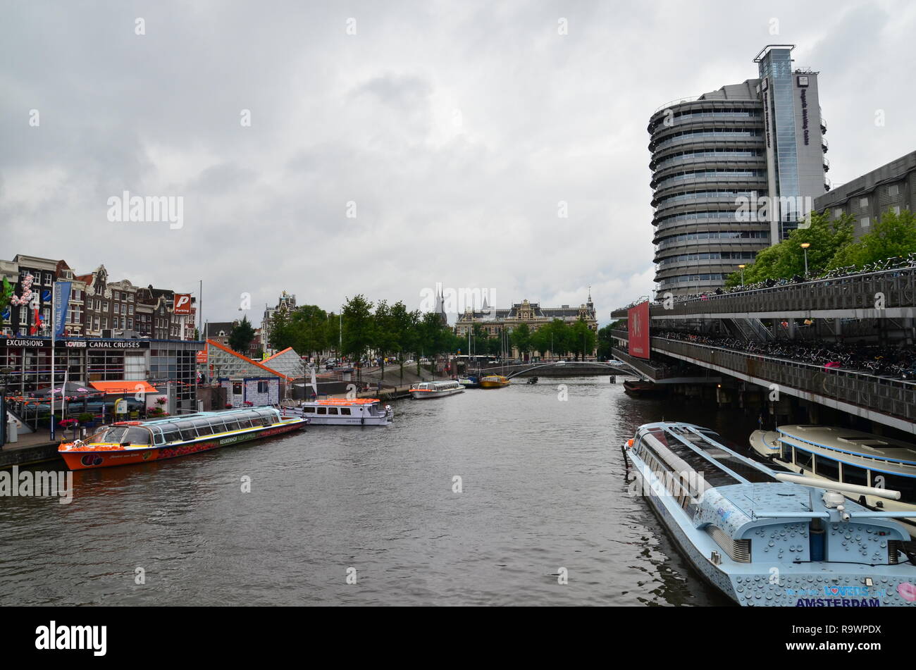 Den Kanal und die Boote, die mit einem Gebäude im Hintergrund in Amsterdam Stockfoto