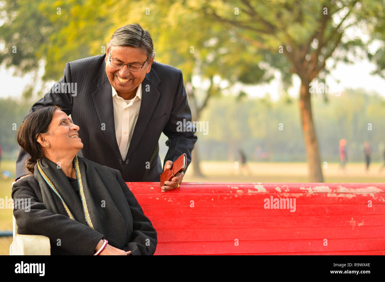 Gerne suchen pensionierte ältere indische Mann und Frau paar Lächeln und sich an der Suche in einem Park im Freien Stockfoto