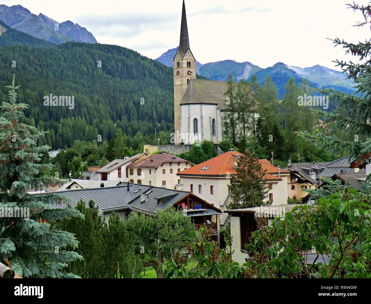 Blick auf die markante Kirche oberhalb der Stadt Scuol durch die Berglandschaft im Unterengadin, Schweiz umgeben Stockfoto