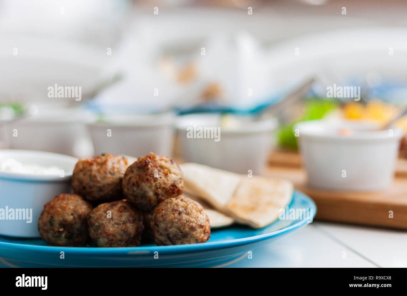 Gebratene Fleischbällchen mit Minze und Apfel mit weißer Soße und flache Kuchen - traditionelle griechische Mittagessen auf einem blauen Platte in einem Restaurant. Stockfoto