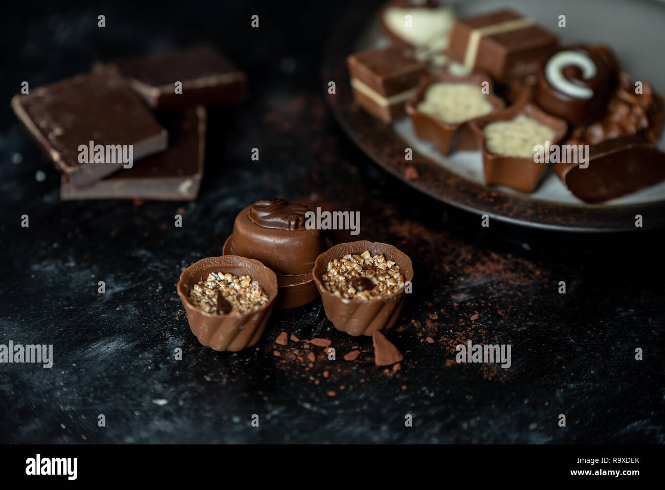 Verschiedene, süße Pralinen von Zartbitter-, Vollmilch- und weißer Schokolade in einer dunklen, hölzernen Hintergrund Stockfoto
