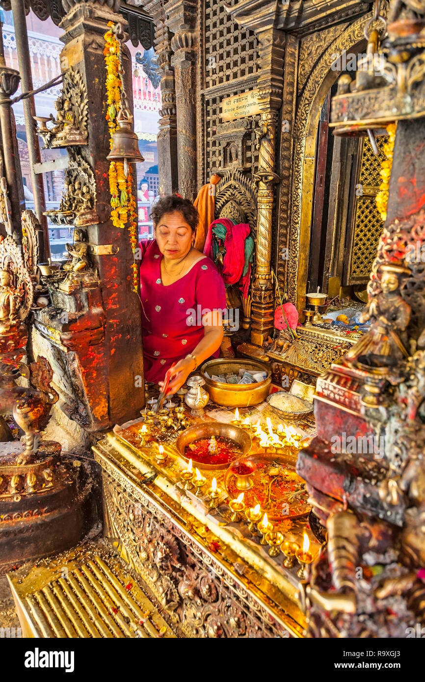 Frau im heiligen Tempel in Kathmandu, Nepal, durch Gold und Blumen umgeben von touristischen Angebote annehmen Stockfoto
