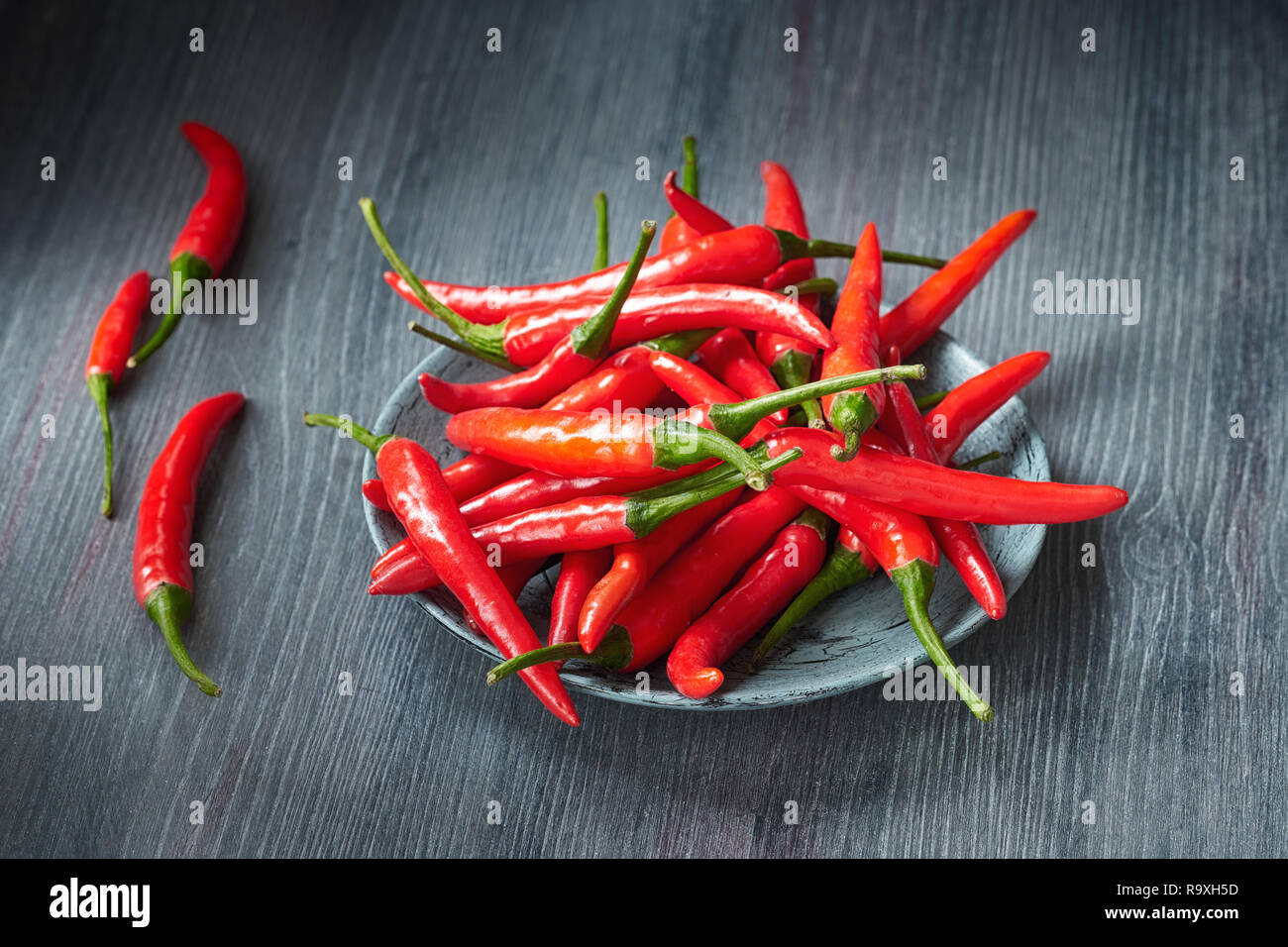 Nahaufnahme auf red hot chili peppers in Stein Schüssel über dunklen Holztisch. Essen Hintergrund. Stockfoto