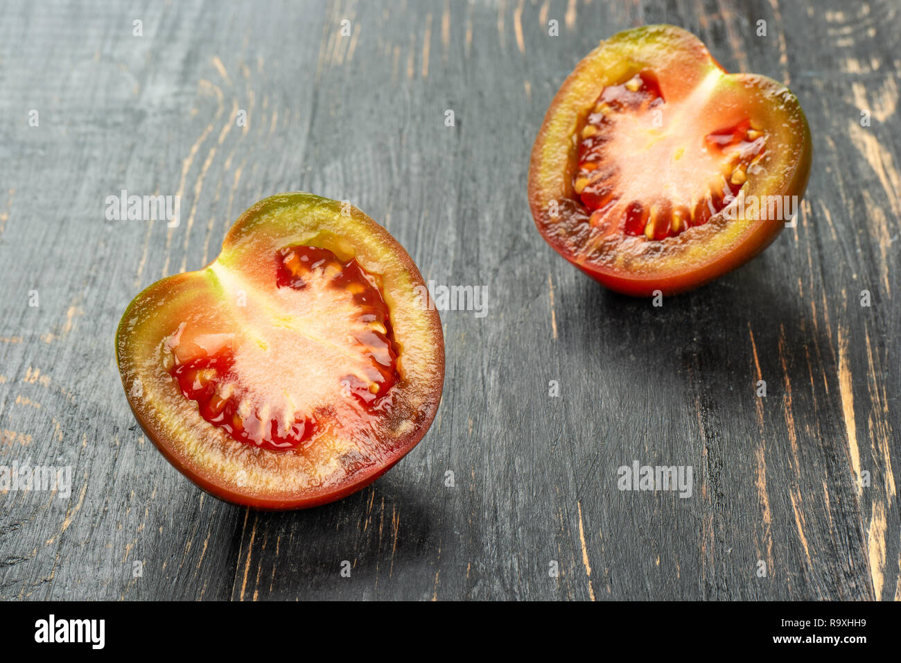 Die beiden Hälften des kumato Tomate auf einen dunklen Tisch Stockfoto