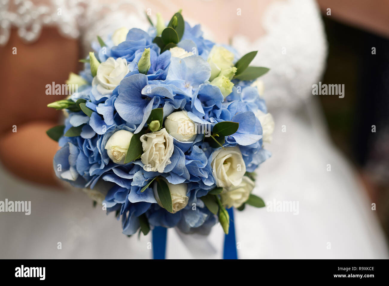 Braut hält in ihrer Hand eine wunderschöne Hochzeit Blumenstrauß aus Rosen und blauen Hortensien Stockfoto