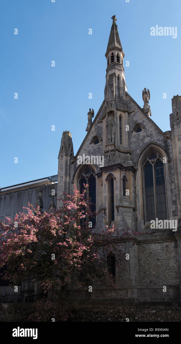 Land Kirche mit Steinfassade, Turm und Engel Statuen, vor einem blauen Himmel mit blühenden Kirschbäume vor Stockfoto