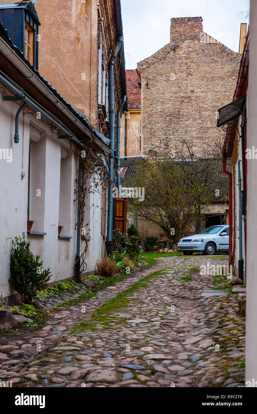 Arch Tore zu mittelalterlichen Pflasterstein grungy, aber stilvoll und gemütlich Straße mit geparkten Auto in der Altstadt von Vilnius. Klassische europäische Architektur str Stockfoto