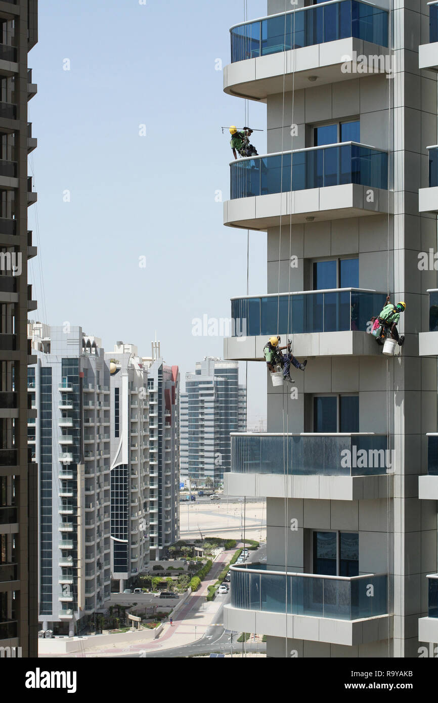 Hochhaus Arbeitnehmer Tragen von Sicherheitsgurten waschen die Fenster eines Hochhauses in Dubai Stockfoto