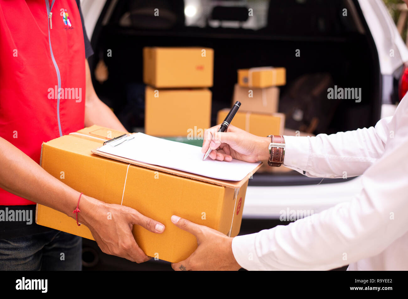 Asiatische junge Mann und Lieferung Arbeiter sind Signatur von Dokumenten für Pakete versenden, Kartons im background-image Stockfoto