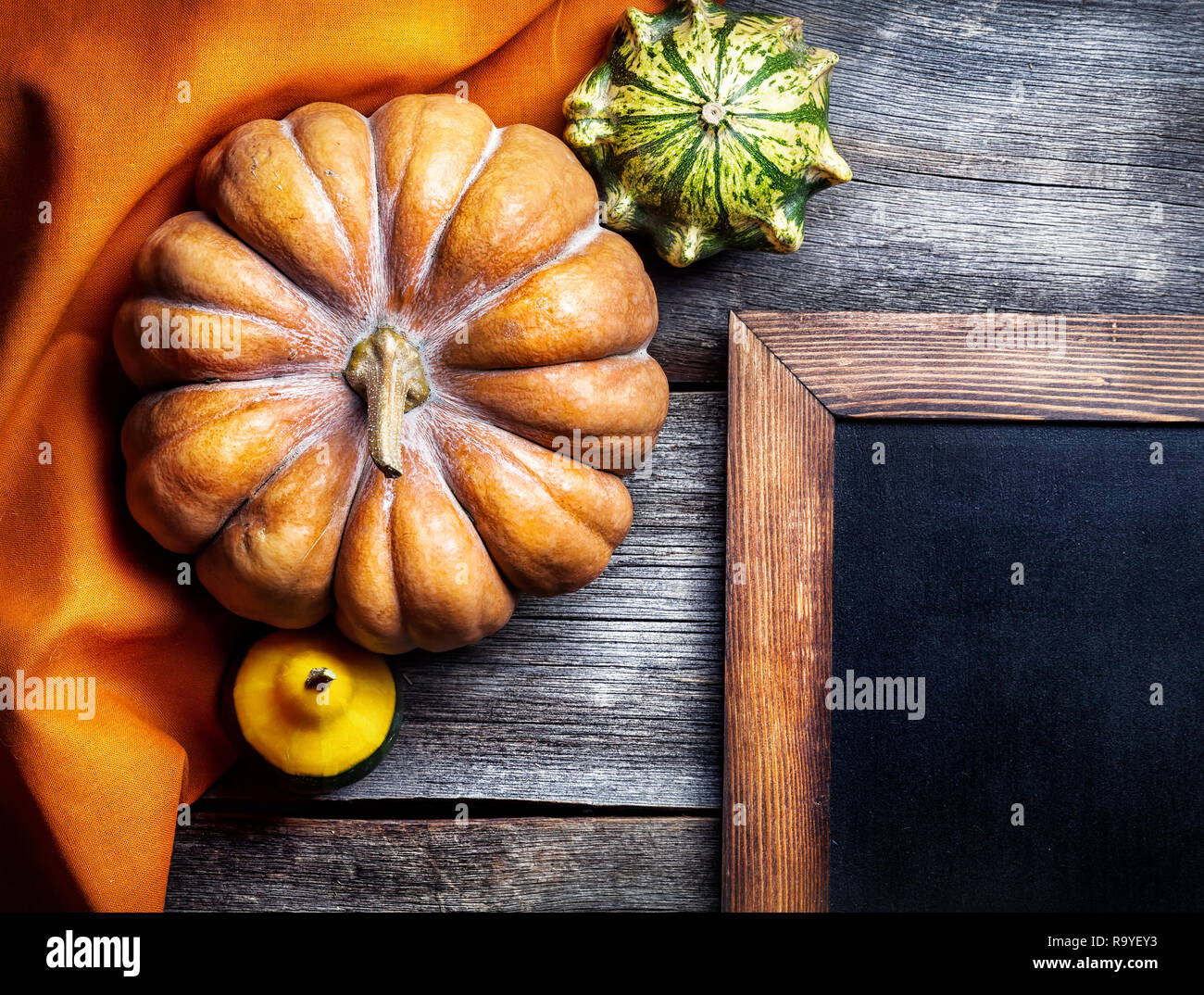 Tafel in der Nähe der Kürbisse auf hölzernen Hintergrund im Herbst Stockfoto