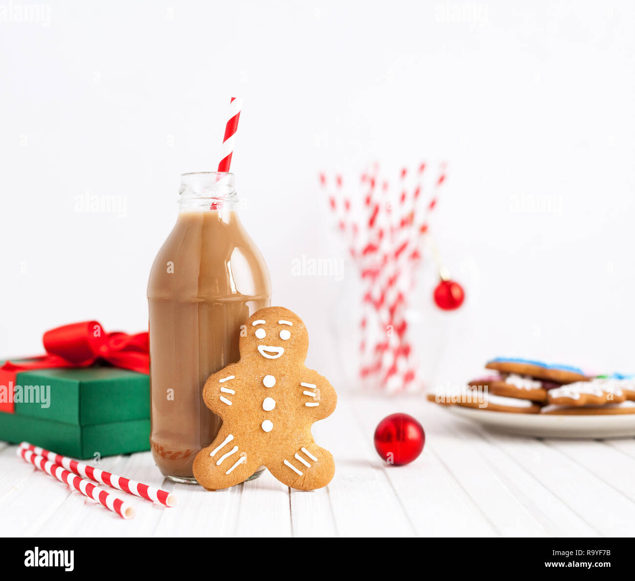 Lebkuchen in der Nähe der Flasche mit Schokolade Milch und abisolierten Stroh auf weißem Hintergrund in der Weihnachtszeit Stockfoto