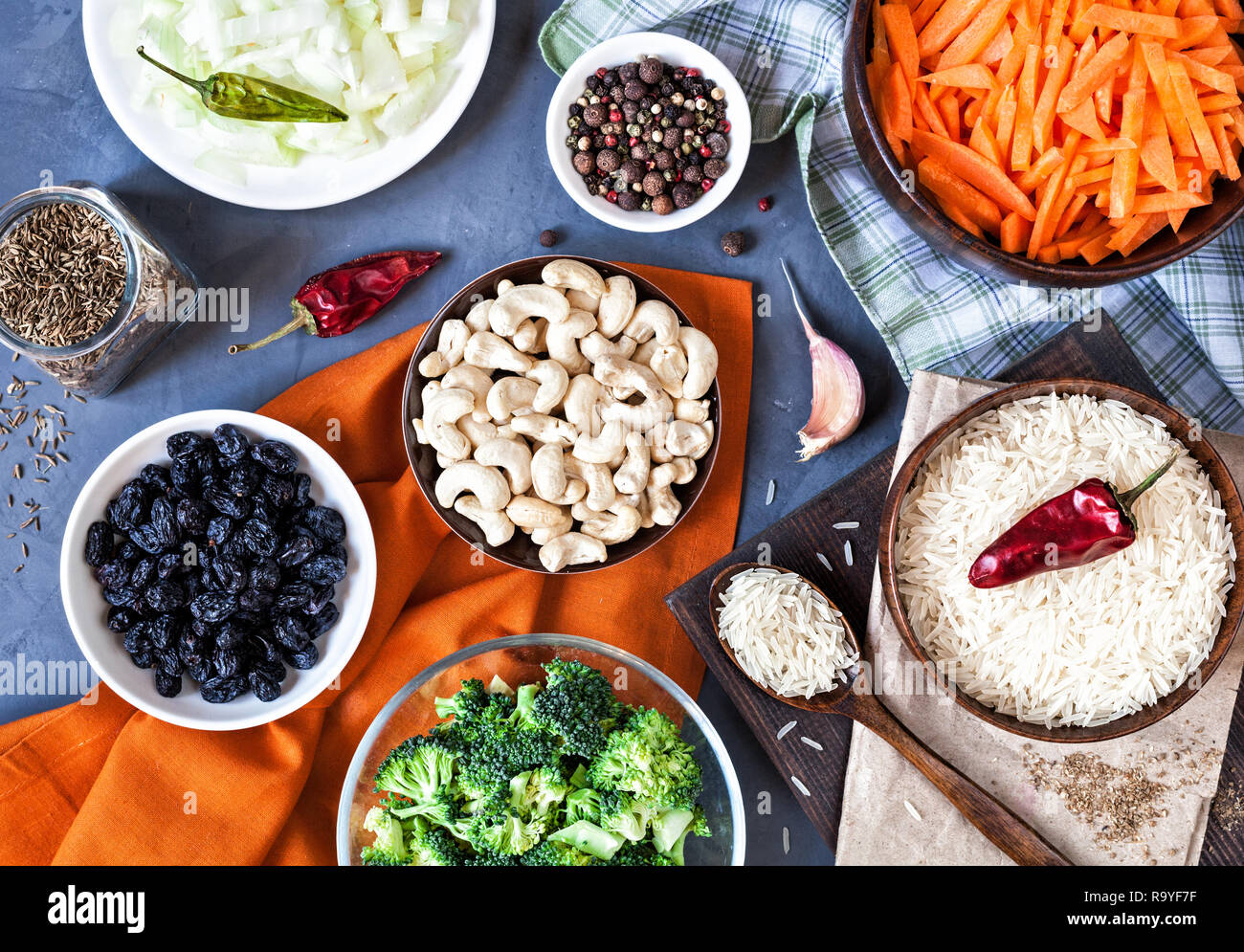 Bestandteile von vegetarischen Pulao mit Cashew Nüssen, Rosinen, Brokkoli und Gewürzen auf grunge Hintergrund Stockfoto