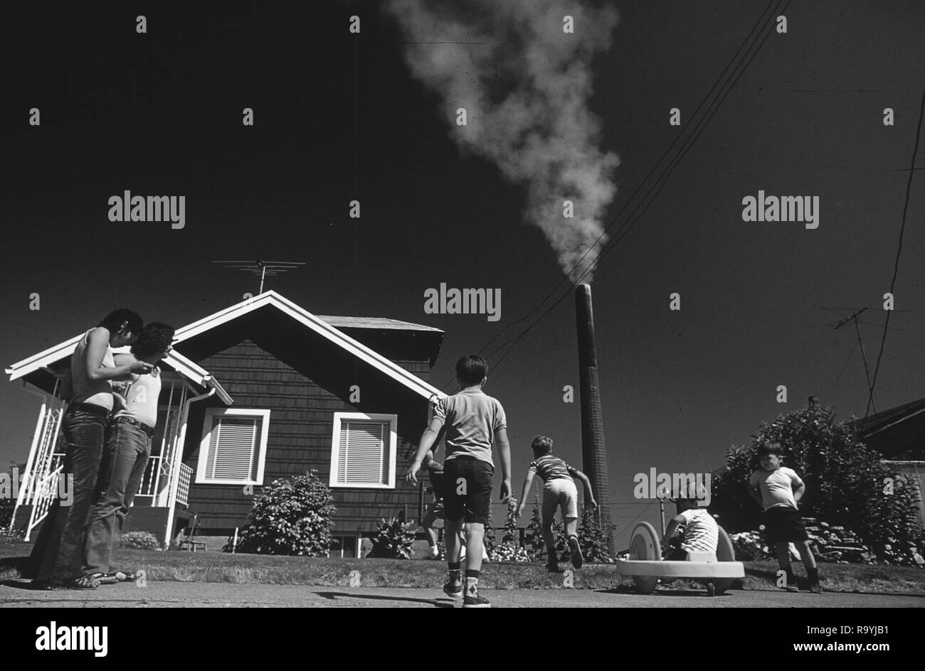 Rauch aufsteigt, aus industriellen Schornsteine in Amerika als Familie mit Kinder spielen in der Nähe Stockfoto