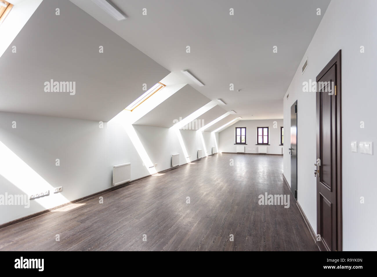 Seitenansicht des unmöblierte Zimmer mit Holzboden auf dem Dach, weiße Wände, helle dayligh Stockfoto