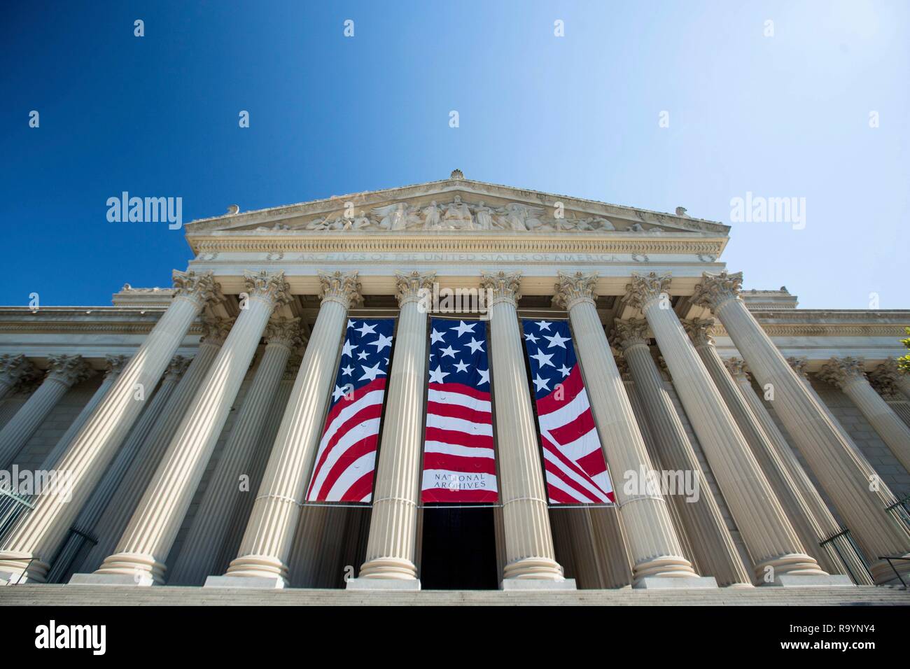 Amerikanische Flagge Banner die Spalten auf der Constitution Avenue Seite der National Archives in Vorbereitung für den vierten Juli Zeremonien zum 28. Juni 2017 in Washington, D.C. Die National Archives Gebäude hält die Originale der drei wichtigsten prägenden Dokumente der Vereinigten Staaten und ihrer Regierung: die Unabhängigkeitserklärung, die Verfassung, und die "Bill of Rights" eingerichtet. Stockfoto
