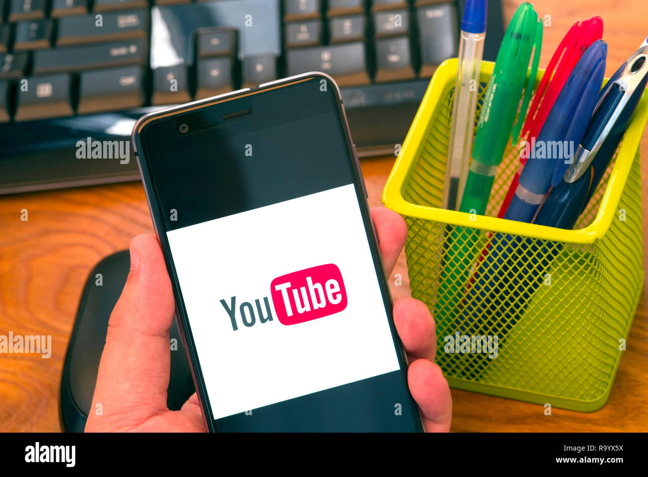 PIATRA Neamt, Rumänien - 30. JULI 2018: Hand hält ein Mobiltelefon mit Youtube auf dem Bildschirm, Büro Hintergrund. Stockfoto