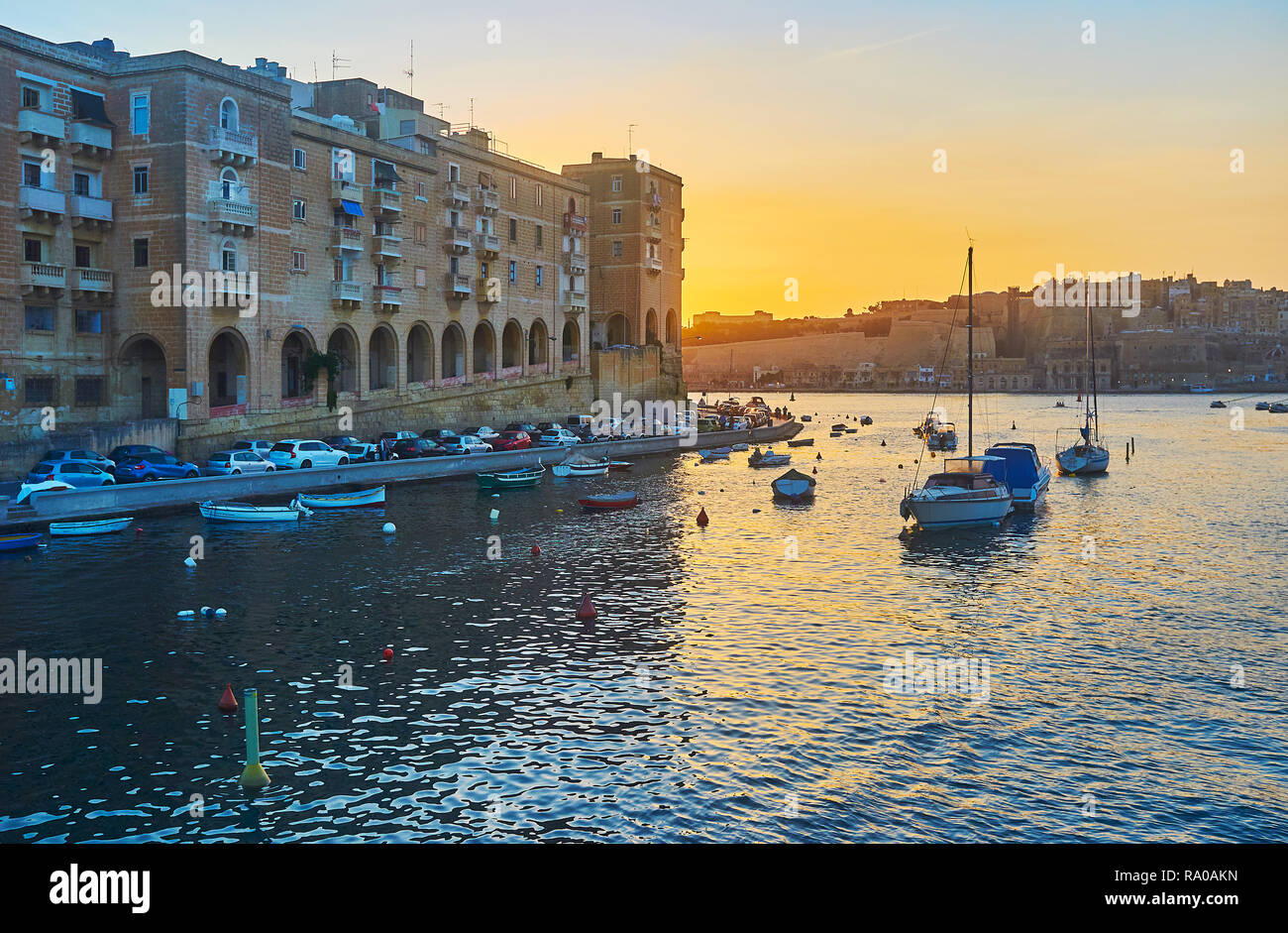 Die feurige Himmel über Valletta Grand Harbour mit Blick auf den mittelalterlichen Bauten der Senglea Valletta, Wände und Fischerboote in Vittoriosa marina, Malta. Stockfoto