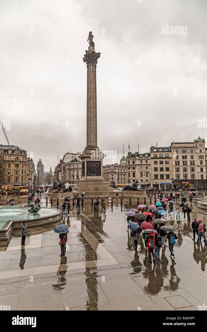 Trafalgar Square, London, England. Touristen die Zuflucht von April regnet unter Sonnenschirmen, mit Nelson's Column im Hintergrund. Stockfoto