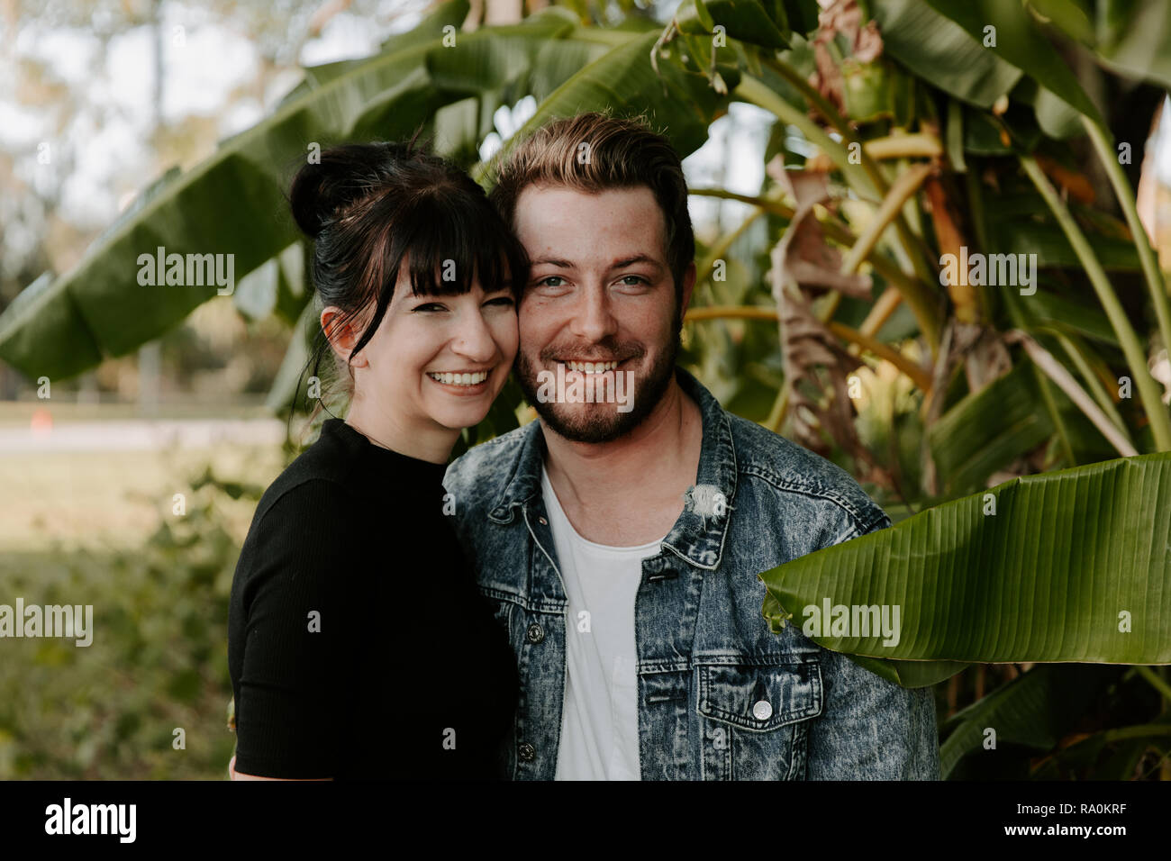 Porträt von zwei niedlichen Moderne kaukasischen Schöne junge Erwachsene Guy Freund Lady Freundin paar Umarmungen und Küsse in Liebe, Natur mit grünen Pflanzen Stockfoto