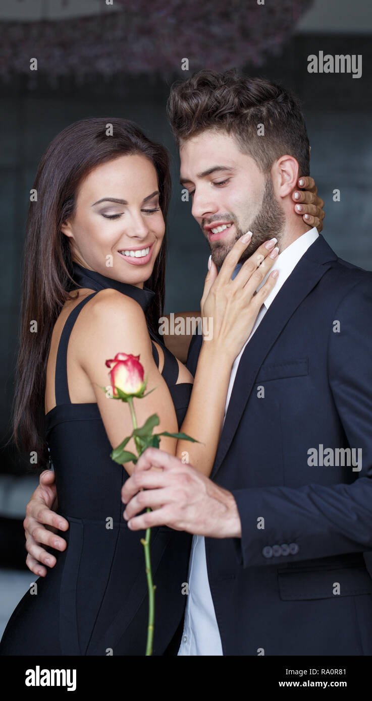 Stilvolle Junge Mann geben rote Rose zu Frau an Valentines Tag drinnen Stockfoto