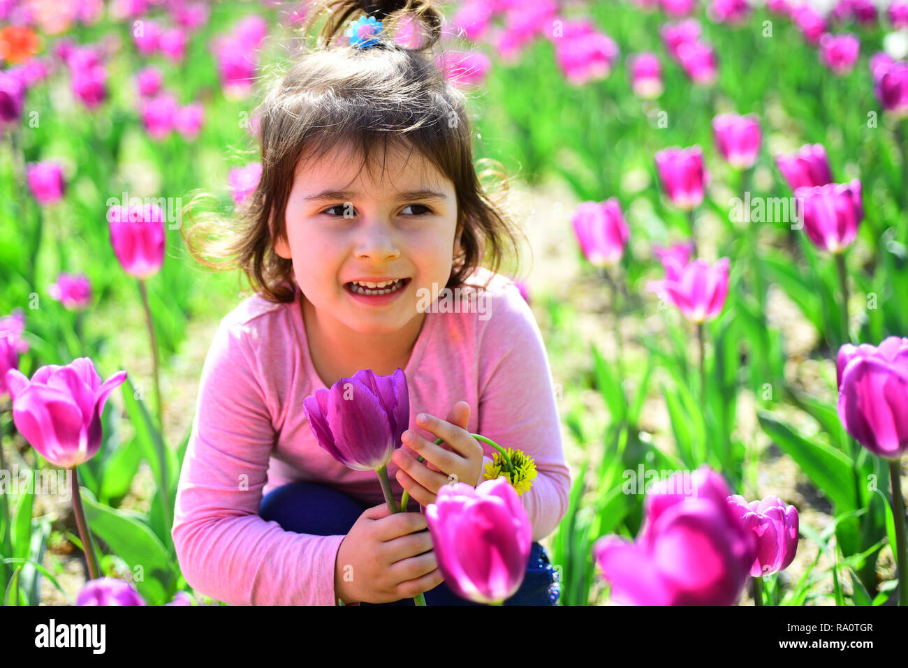 Frühling Schönheit. Kleines Mädchen im sonnigen Frühling. Sommer Mädchen Mode. Glückliche Kindheit. Gesicht Hautpflege. Allergie zu Blumen. Frühling Tulpen. Wetter foreca Stockfoto