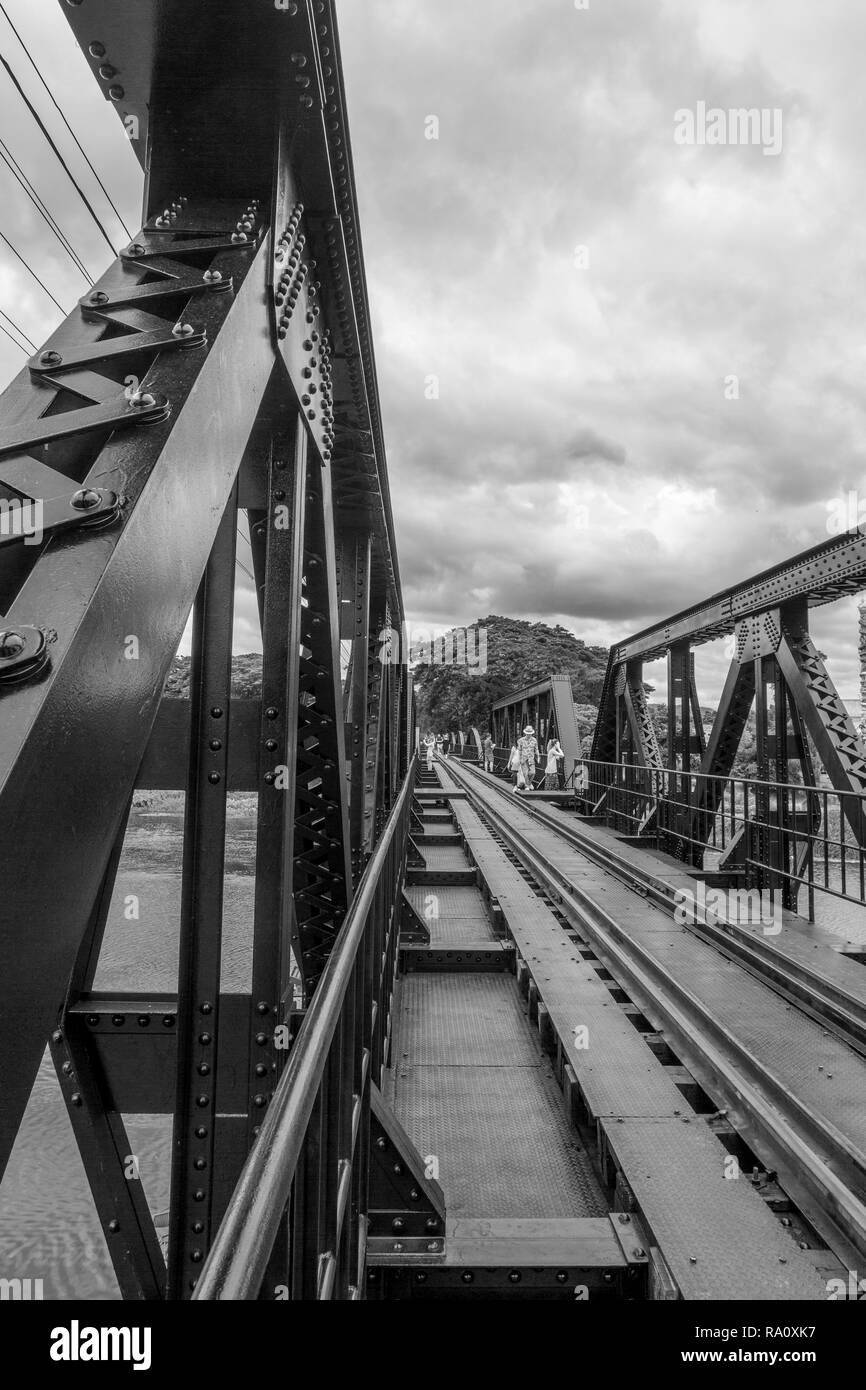 Schwarze und weiße Blick vom Geländer der Brücke über den River Kwai. Die Menschen gehen in die Ferne. Stockfoto