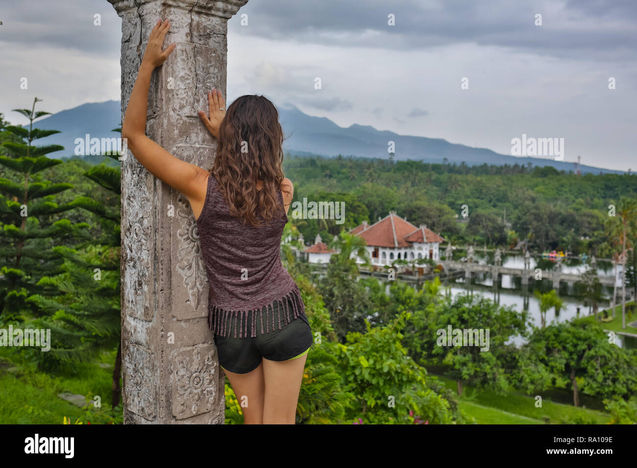 Serie reisen Mädchen in Asien. schöne Mädchen mit langen dunklen Haaren in eleganten grauen Kleid auf der alten Brücke in Tirta Gangga wasser Tempel posiert in Bali Stockfoto