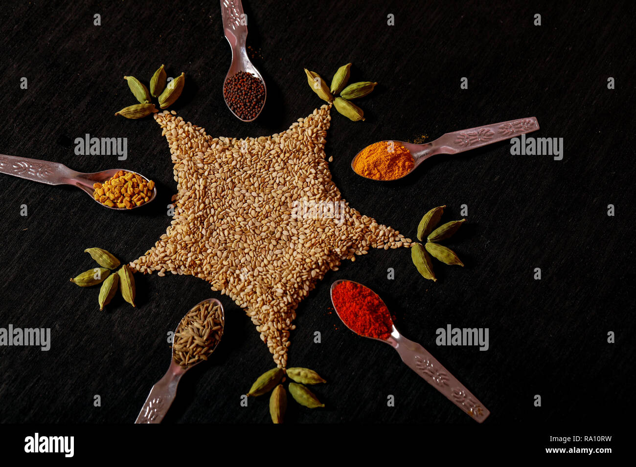 Gewürze in Löffel auf schwarzem Hintergrund Stockfoto