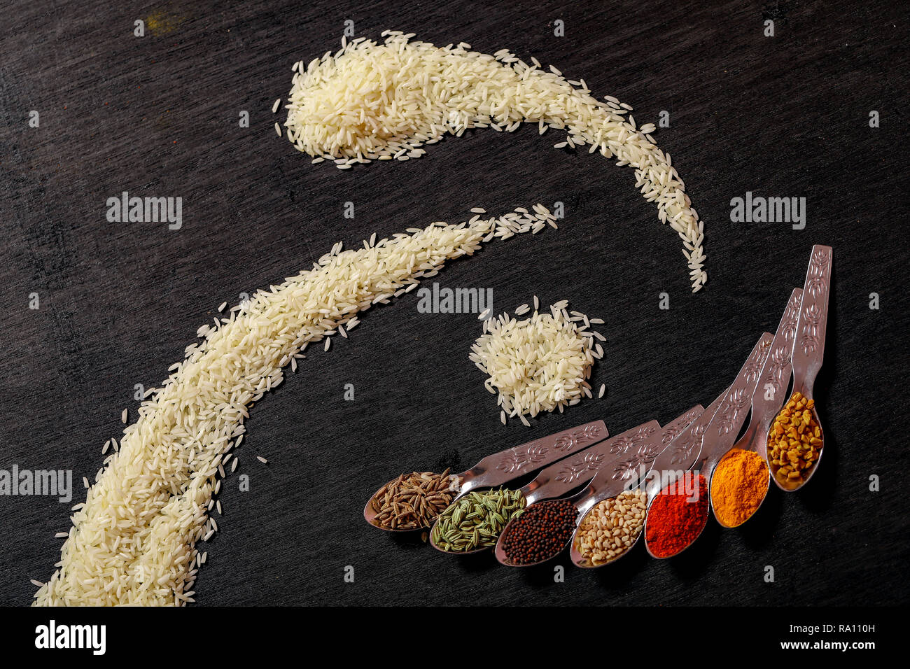 Gewürze in Löffel auf schwarzem Hintergrund Stockfoto